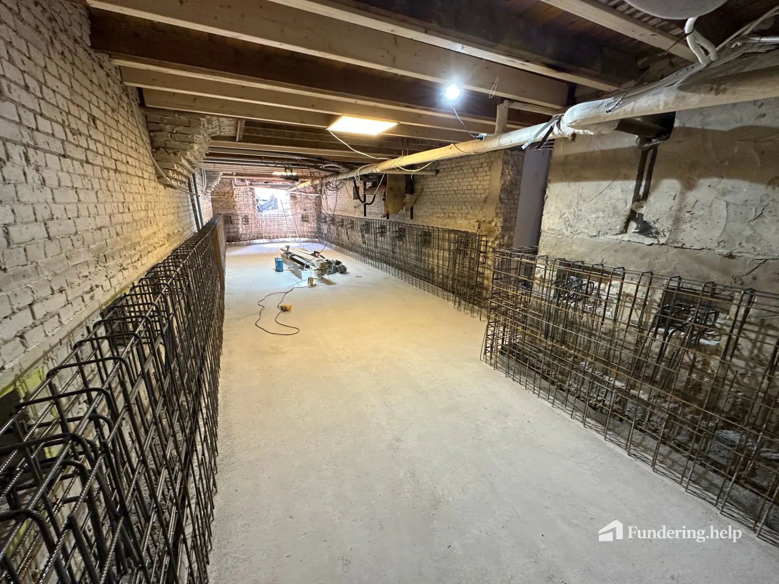 Wapening voor nieuwe betonwanden langs het metselwerk van een souterrain