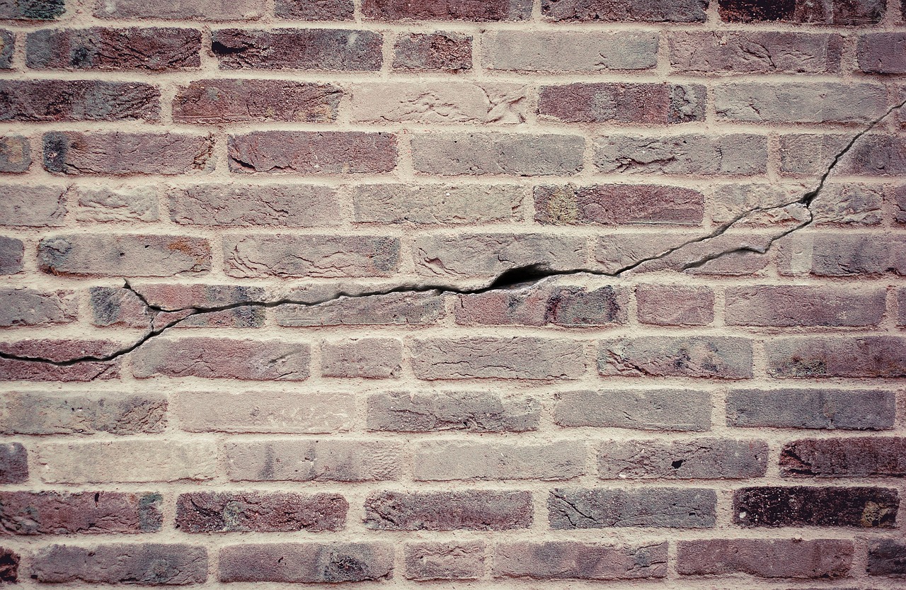 Brede scheur in een gemetselde gevel, dwars door meerdere steenlagen