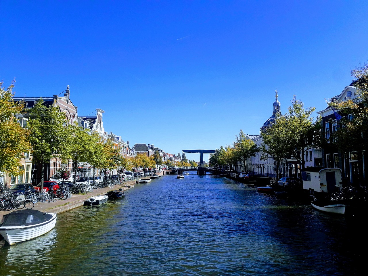 Gracht in Leiden met historische gevels, boten en bomen; de oude panden staan op houten palen in veen en klei