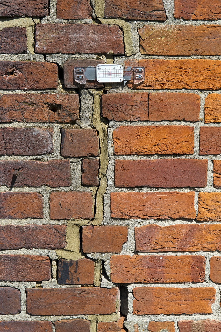 Scheurmeter met meetschaal gemonteerd over een doorlopende scheur in een bakstenen muur