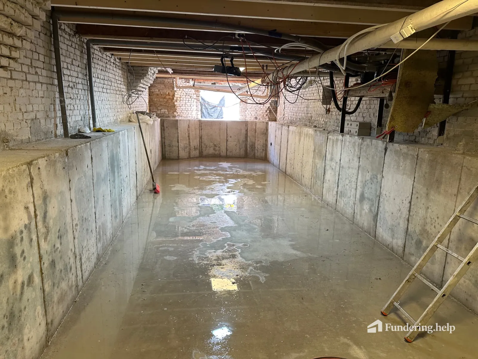 Ontkiste betonnen kelderbak met natte vloer onder een bestaande woning