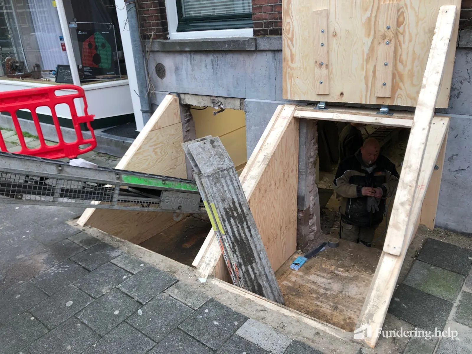 Afvoer van grond via een opening in de gevel tijdens funderingsherstel