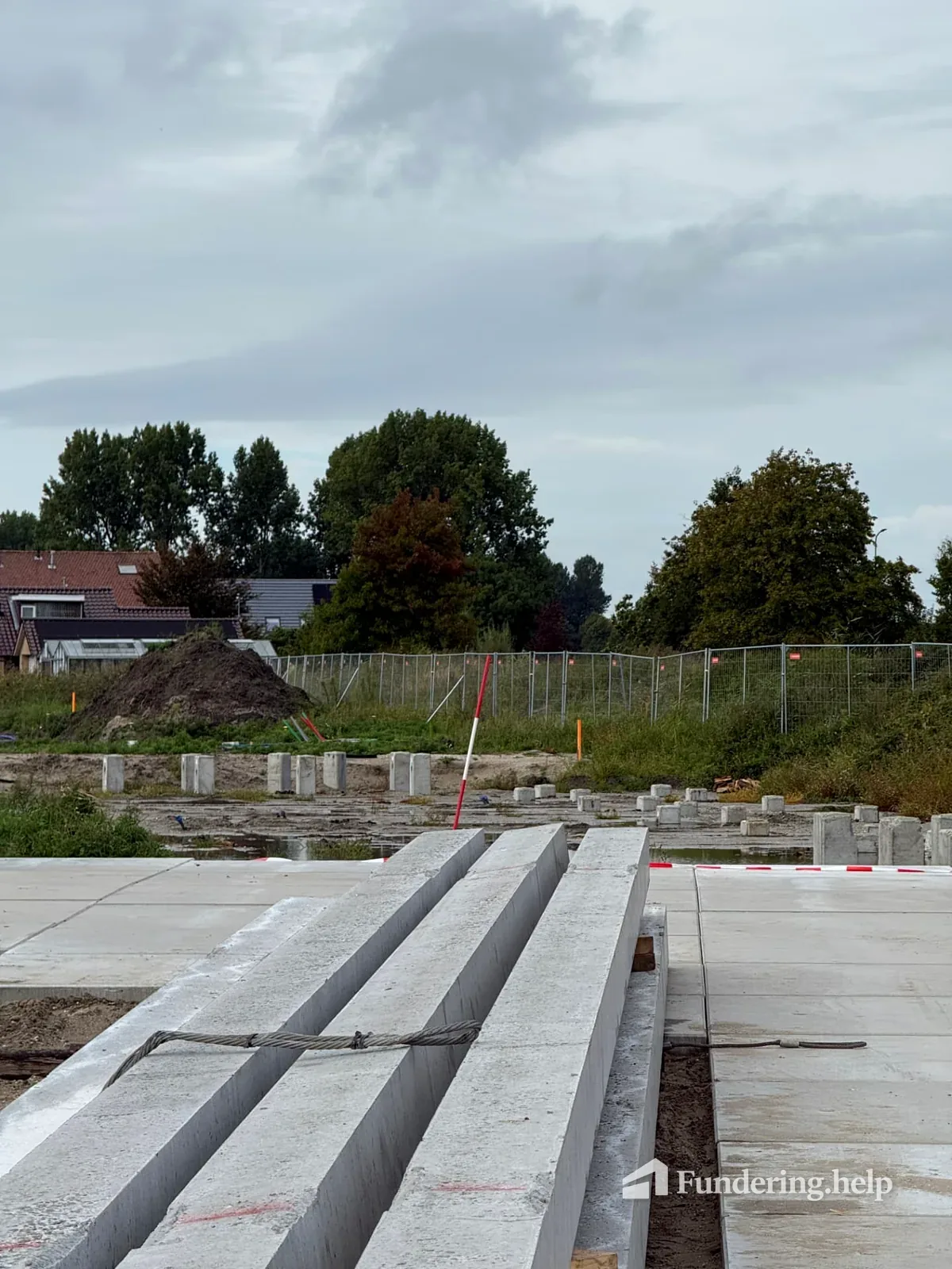 Losse prefab betonpalen naast aangebrachte paalkoppen in een nieuwe fundering