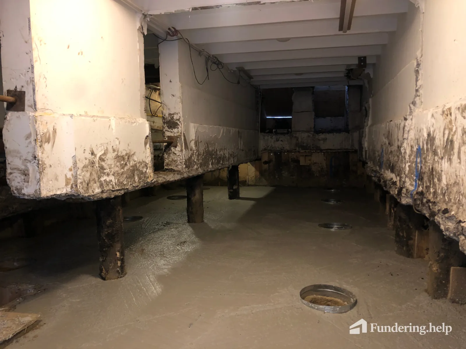 Uitgegraven ruimte onder een woning met vrijgelegde houten paalkoppen onder het oude metselwerk