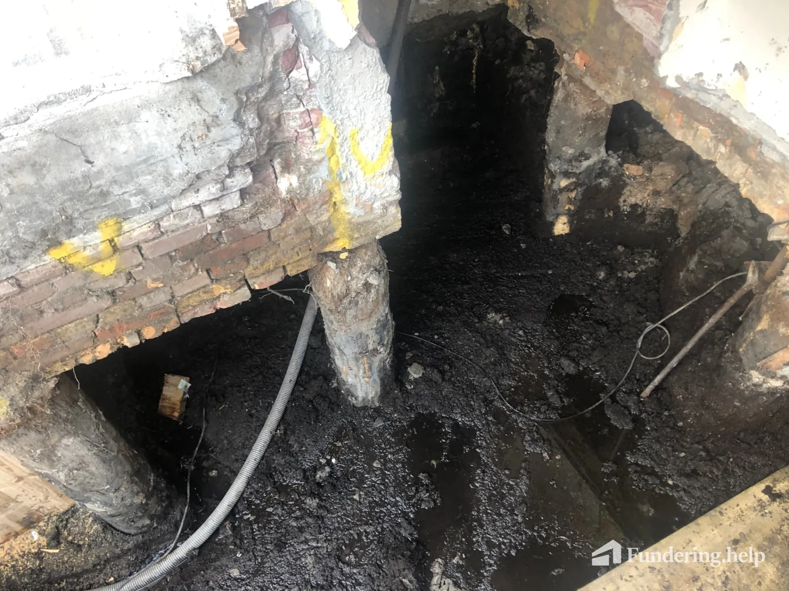Vrijgegraven houten paalkoppen met aantasting onder een oude woning
