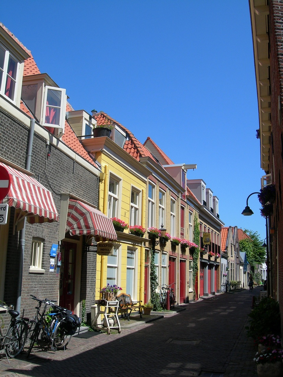 Historische straat in Delft met karakteristieke gevels, rode daken en luifels; de oude panden staan op houten palen in klei en veen