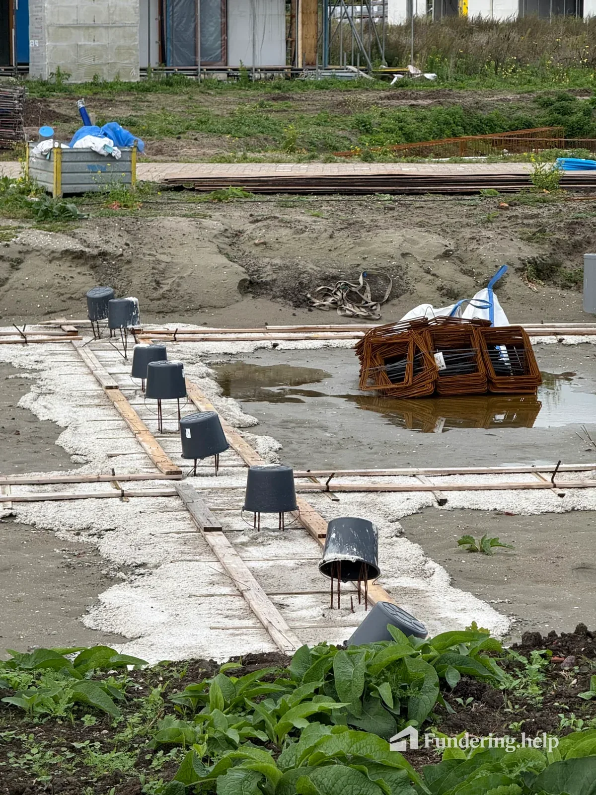 Woningfundering in aanbouw met betonnen stroken, wapening en aansluitpunten