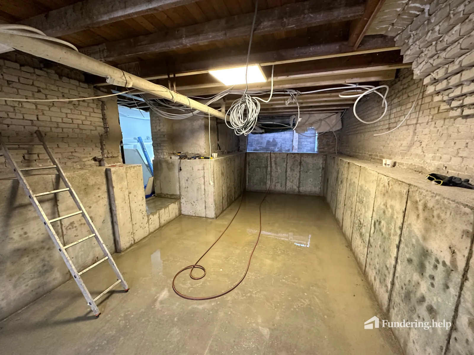 Nieuwe betonnen kelder met trap en ladder onder een bestaande woning